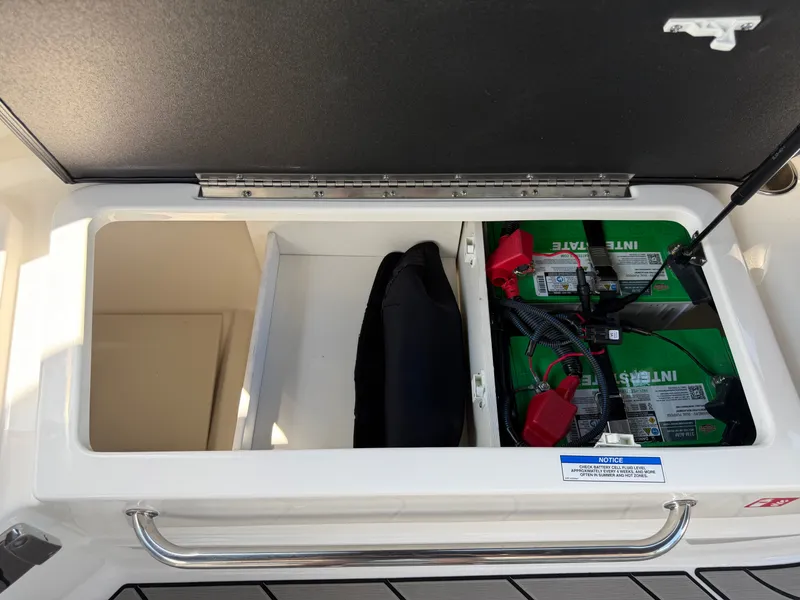 Slide: The Image of View of a storage compartment with batteries and a life jacket on a Sea Ray SLX 260 boat. - 49