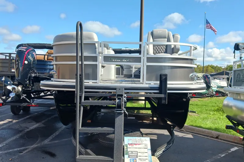 Slide: The Image of 2025 Ranger Reata 220FC pontoon boat on display with American flag in background. - 2