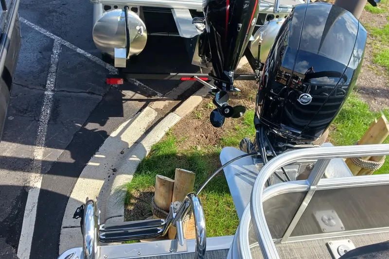 Slide: The Image of 2025 Ranger Reata 220FC boat with dual outboard motors in a parking area. - 5