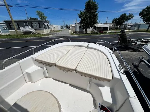 Slide: The Image of 2016 Carolina Skiff 218 DLV boat with cushioned seating, parked near residential area. - 10