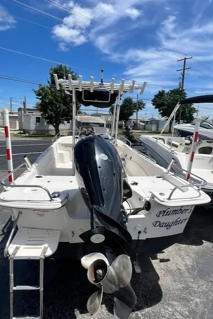 Slide: The Image of 2016 Carolina Skiff 218 DLV boat with outboard motor, docked under a clear blue sky. - 15