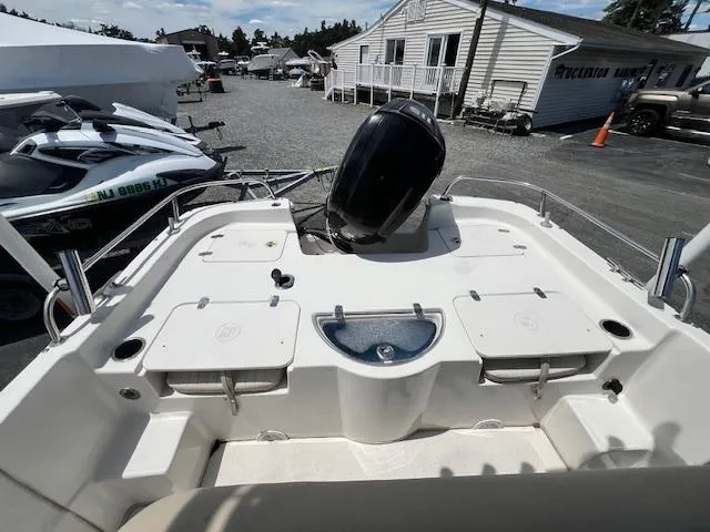 Slide: The Image of 2016 Carolina Skiff 218 DLV boat with outboard motor, docked near jet skis. - 8