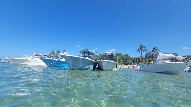 Slide: The Image of Boats anchored in clear water near a tropical beach, featuring a 2022 Sea Hunt Gamefish 30. - 21