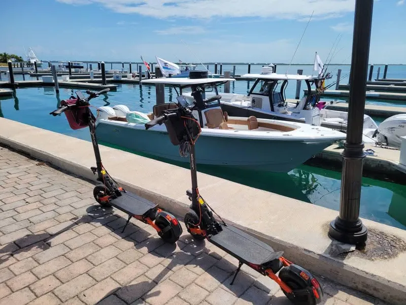 Slide: The Image of 2022 Sea Hunt Gamefish 30 boat docked, with two electric scooters in the foreground. - 23