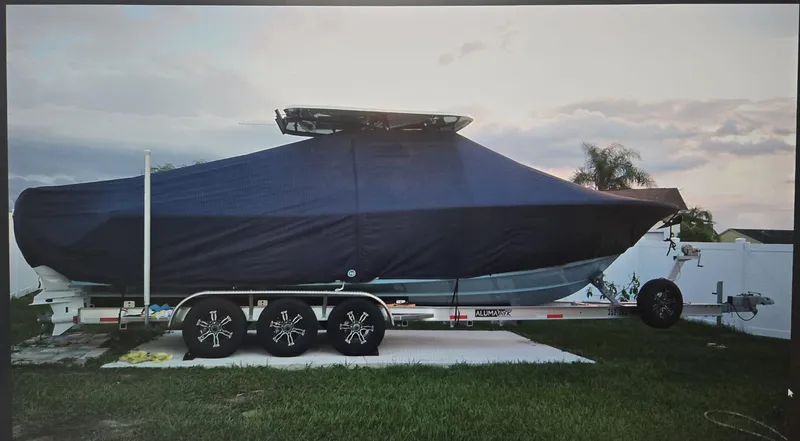 Slide: The Image of 2022 Sea Hunt Gamefish 30 boat covered on trailer, parked on grass. - 24