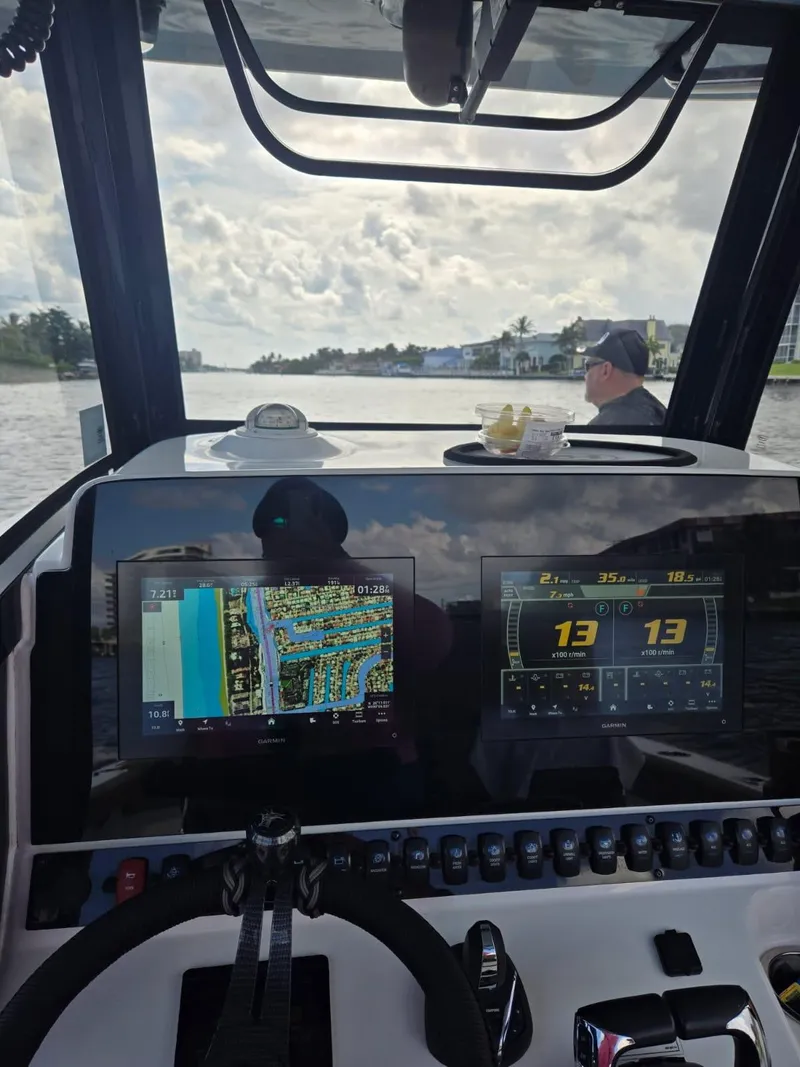 Slide: The Image of 2022 Sea Hunt Gamefish 30 helm with navigation screens, steering wheel, and waterway view. - 26