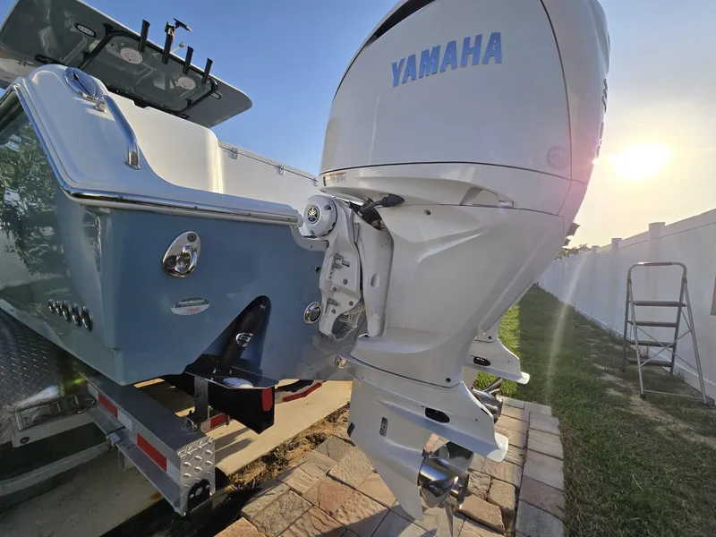 Slide: The Image of 2022 Sea Hunt Gamefish 30 with Yamaha outboard engine, parked on a trailer in sunlight. - 30