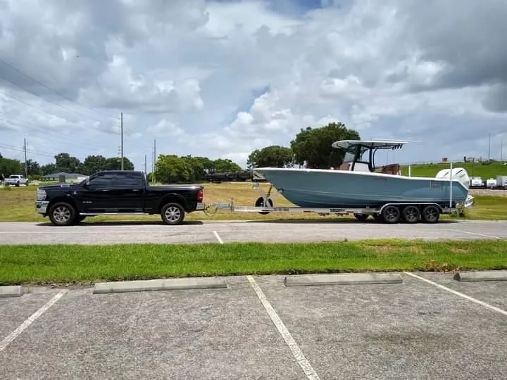 Slide: The Image of 2022 Sea Hunt Gamefish 30 boat on trailer, towed by a black truck in a parking lot. - 35