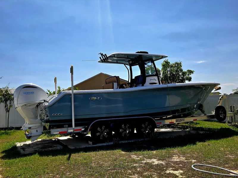 Slide: The Image of 2022 Sea Hunt Gamefish 30 boat on trailer, blue hull, parked outdoors. - 36