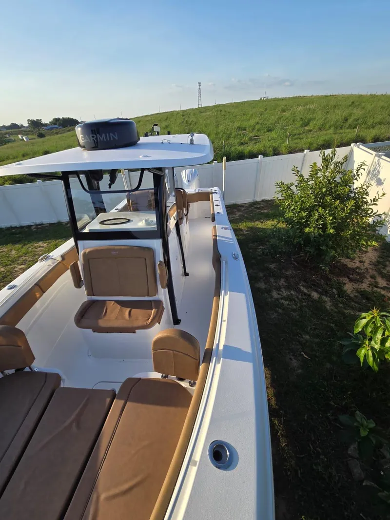 Slide: The Image of 2022 Sea Hunt Gamefish 30 boat with forward seating, docked near a grassy area. - 7