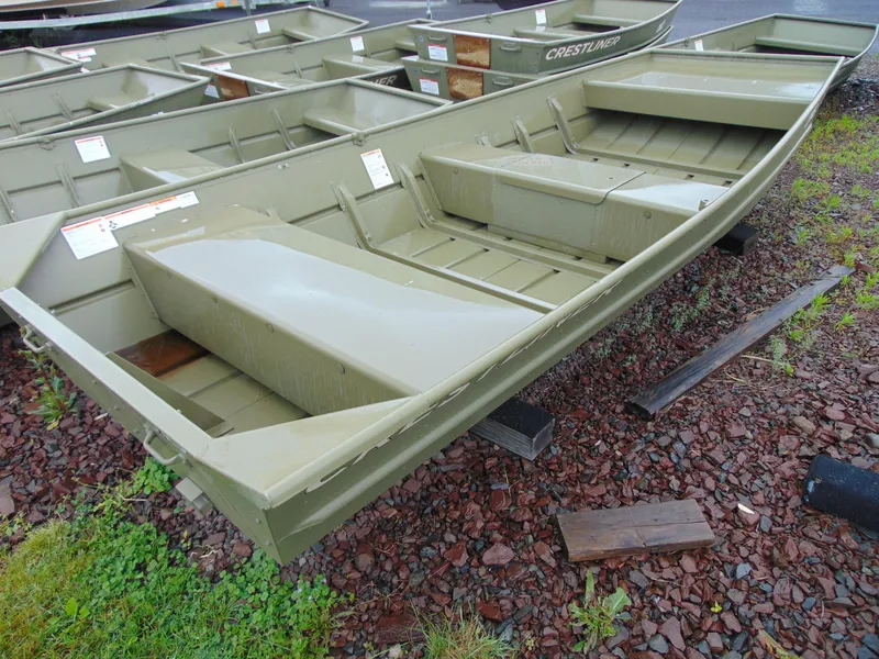 Slide: The Image of 2024 Crestliner 1448M CR Jon boat on rocky ground, showcasing its durable design. - 3