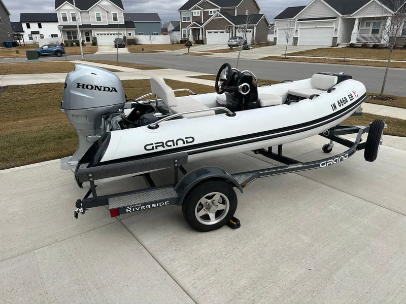 Slide: The Image of 2022 Grand Inflatables G380 boat with Honda motor on trailer in suburban driveway. - 1