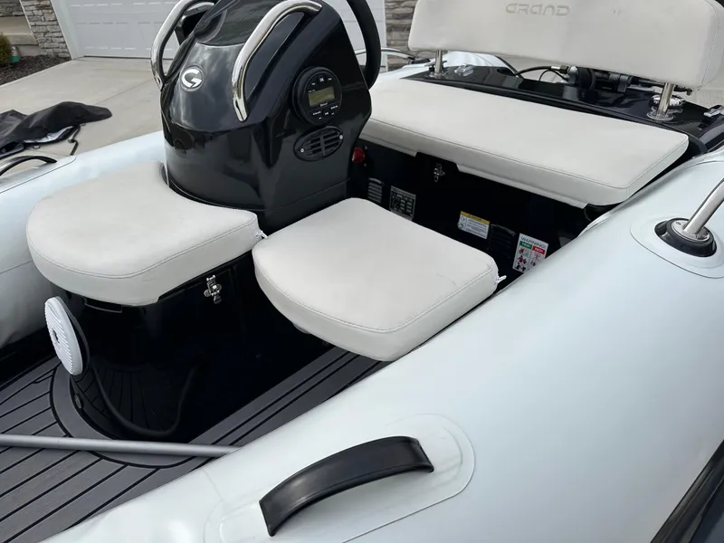 Slide: The Image of 2022 Grand Inflatables G380 boat interior with white seating and black console. - 11