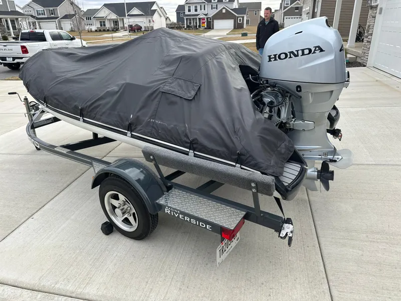 Slide: The Image of 2022 Grand Inflatables G380 boat on trailer with Honda outboard motor, covered and parked. - 3