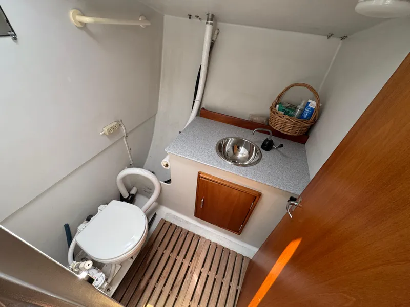 Slide: The Image of Compact bathroom in a 2000 Wyliecat 48 sailboat with toilet, sink, and wooden flooring. - 10