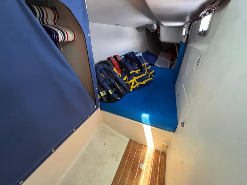 Slide: The Image of Cozy cabin interior of 2000 Wyliecat 48 sailboat with life jackets and blue bedding. - 12