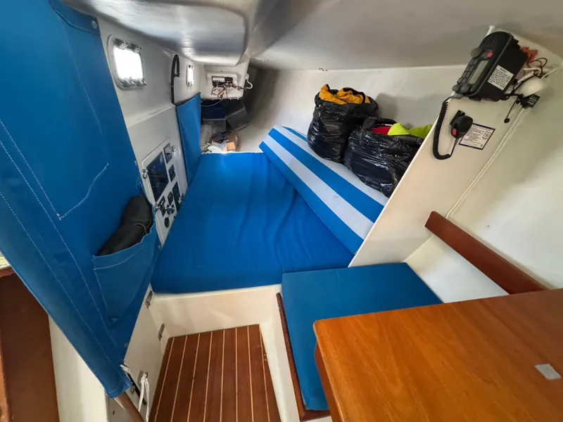 Slide: The Image of Interior of a 2000 Wyliecat 48 sailboat with blue cushions and wooden table. - 14