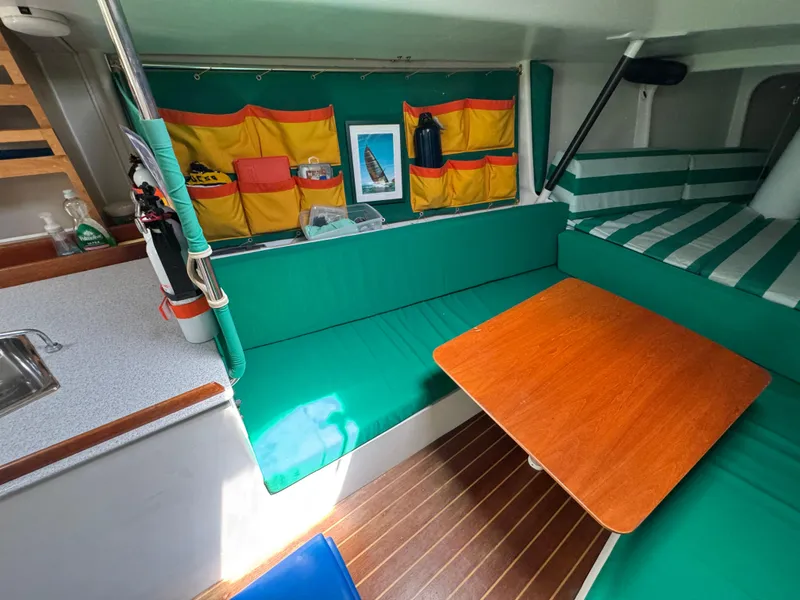 Slide: The Image of Interior of 2000 Wyliecat 48 sailboat with green seating and wooden table. - 6