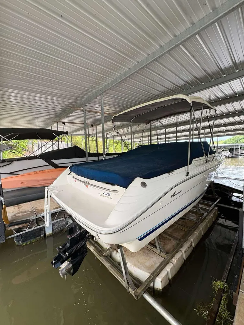 Slide: The Image of 1994 Sea Ray 220 Bow Rider docked under a metal canopy. - 2