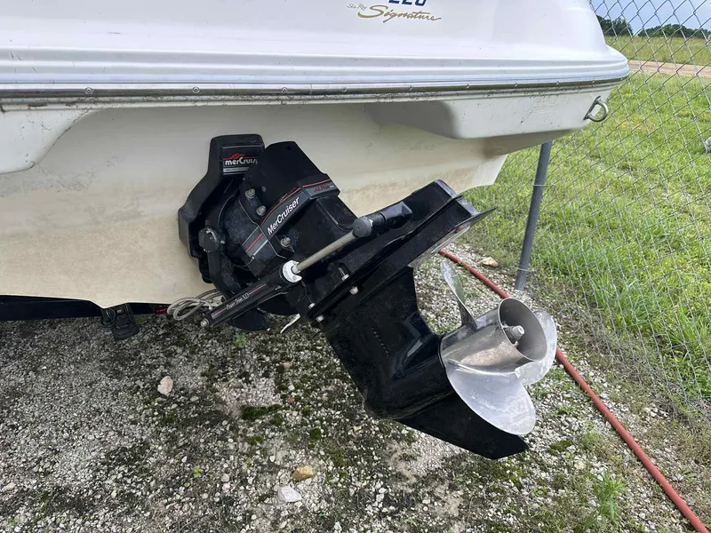 Slide: The Image of 1994 Sea Ray 220 Bow Rider with MerCruiser outdrive, parked on gravel near a chain-link fence. - 24