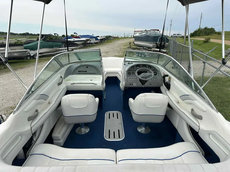 Slide: The Image of 1994 Sea Ray 220 Bow Rider interior with white seating and blue carpet, parked outdoors. - 26