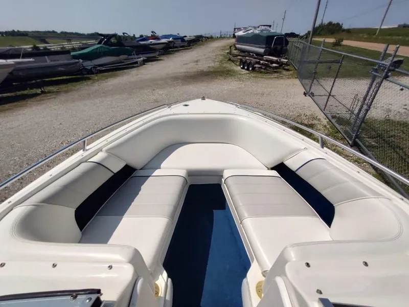 Slide: The Image of 1994 Sea Ray 220 Bow Rider with spacious seating, parked on a gravel lot. - 7
