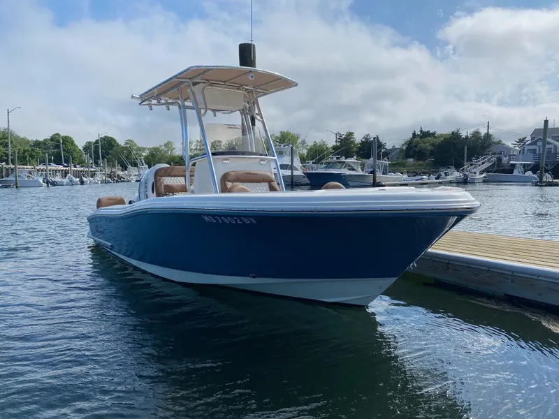 Slide: The Image of 2023 Pioneer 202 Sportfish boat docked in a marina, calm water, clear sky. - 0