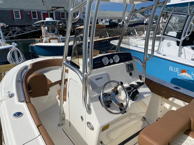 Slide: The Image of 2023 Pioneer 202 Sportfish boat interior with steering console and seating at a marina. - 3