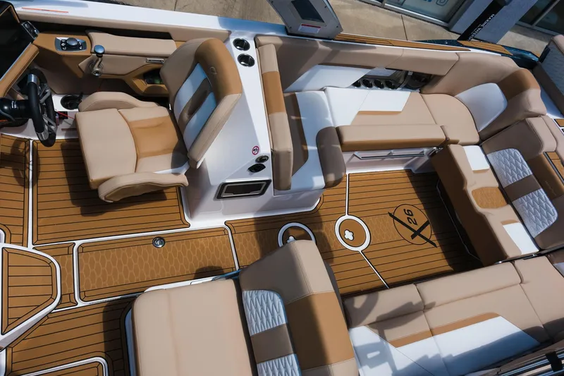 Slide: The Image of 2025 MasterCraft X26 boat interior with tan seating and wood-style flooring. - 32
