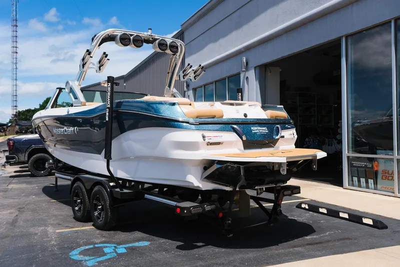 Slide: The Image of 2025 MasterCraft X26 boat on trailer outside dealership, showcasing sleek design and modern features. - 7
