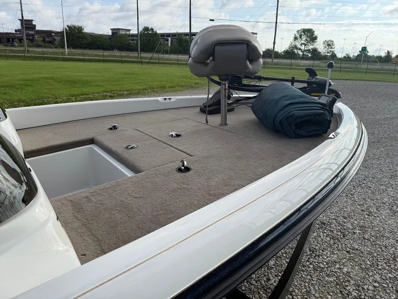 Slide: The Image of 2003 Ranger 185 VS boat deck with seating and storage, parked on gravel near grassy area. - 2