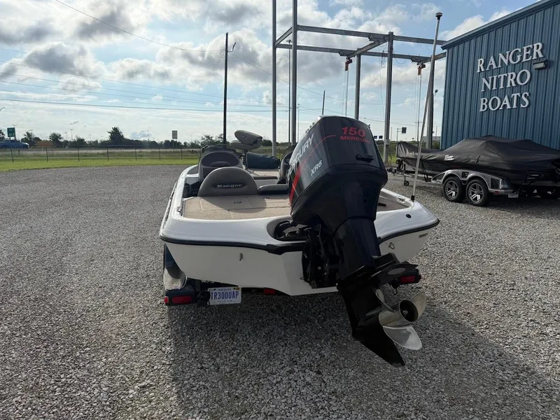 Slide: The Image of 2003 Ranger 185 VS boat with outboard motor, parked on gravel near Ranger Nitro Boats building. - 6