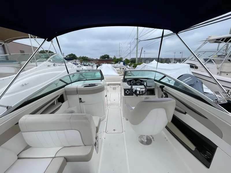 Slide: The Image of 2013 Sea Ray 240 Sundeck interior with helm and seating, docked among other boats. - 10