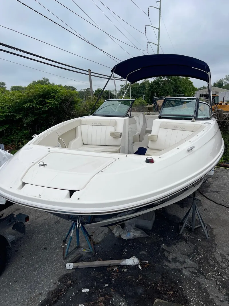 Slide: The Image of 2013 Sea Ray 240 Sundeck boat with canopy, parked on stands, overcast sky. - 3