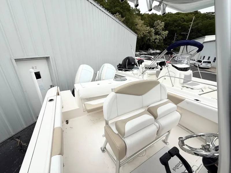 Slide: The Image of 2018 Robalo R242 Explorer boat interior with seating and steering wheel, docked near a building. - 9
