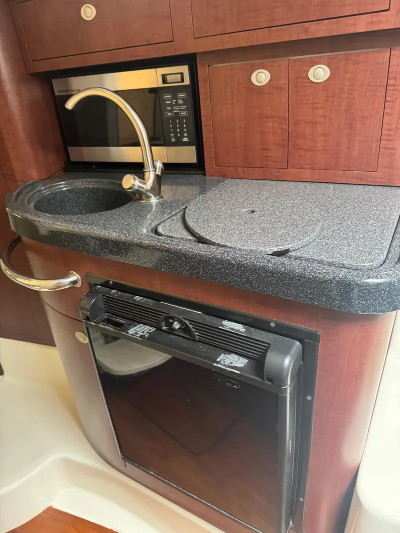 Slide: The Image of 2011 Boston Whaler 305 Conquest kitchen with sink, microwave, and fridge. - 13