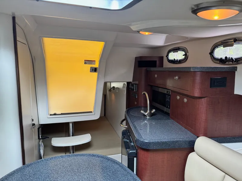 Slide: The Image of 2011 Boston Whaler 305 Conquest cabin interior with kitchenette and seating area. - 14