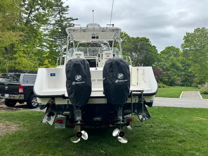 Slide: The Image of 2011 Boston Whaler 305 Conquest boat with dual Mercury engines, parked on grass. - 2