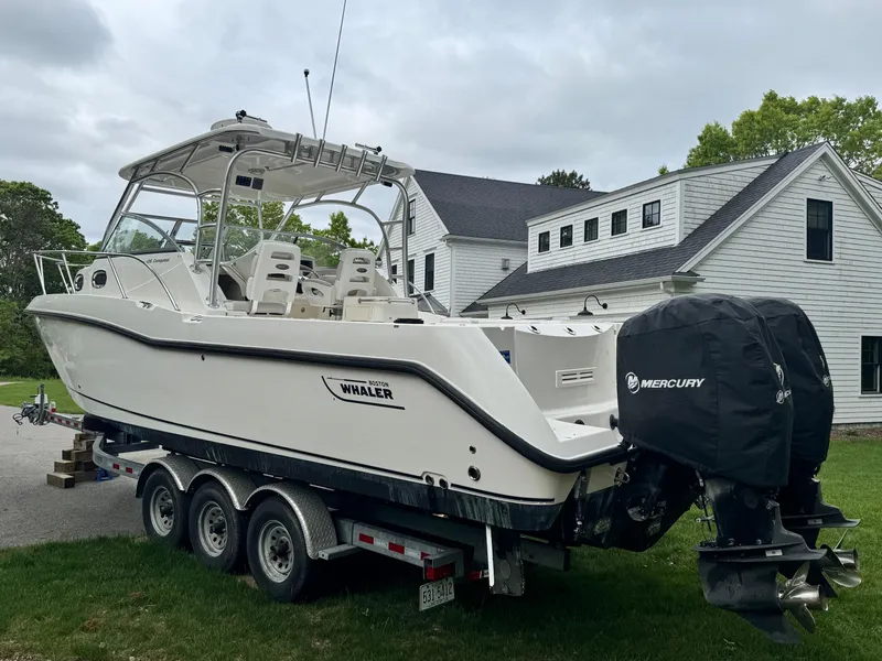 Slide: The Image of 2011 Boston Whaler 305 Conquest boat on trailer, parked near a house. - 3