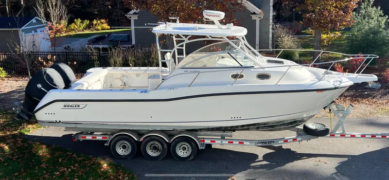Slide: The Image of 2011 Boston Whaler 305 Conquest boat on trailer, parked outdoors in a residential area. - 6