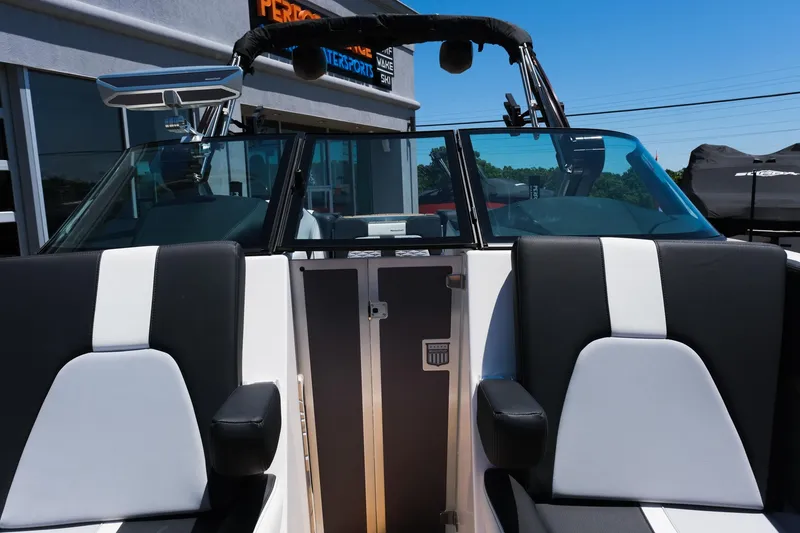 Slide: The Image of 2023 MasterCraft X24 boat interior with black and white seating, docked outdoors. - 32