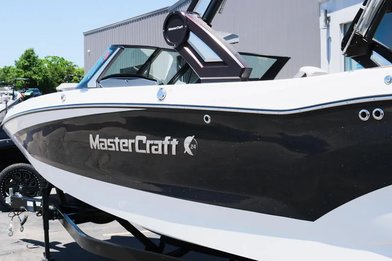 Slide: The Image of 2023 MasterCraft X24 boat with sleek black and white design, parked outdoors. - 37