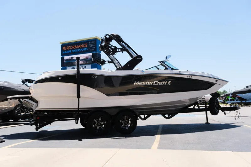 Slide: The Image of 2023 MasterCraft X24 boat on trailer, displayed outdoors under clear sky. - 38
