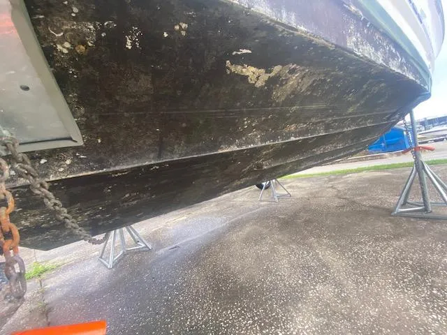 Slide: The Image of 1998 Bayliner Ciara 2855 boat hull on stands, showing wear and marine growth. - 13