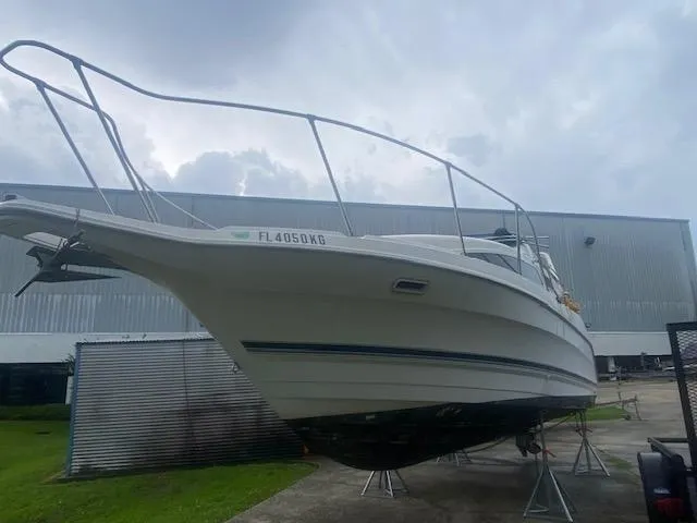 Slide: The Image of 1998 Bayliner Ciara 2855 boat on stands, outdoor storage, overcast sky. - 3