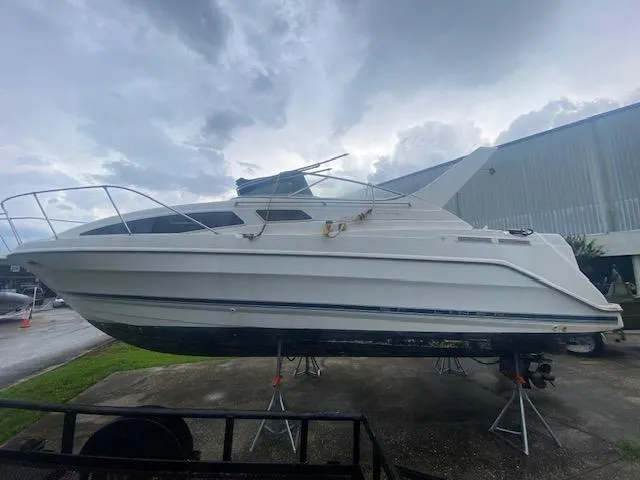 Slide: The Image of 1998 Bayliner Ciara 2855 boat on stands, outdoor setting, cloudy sky. - 4