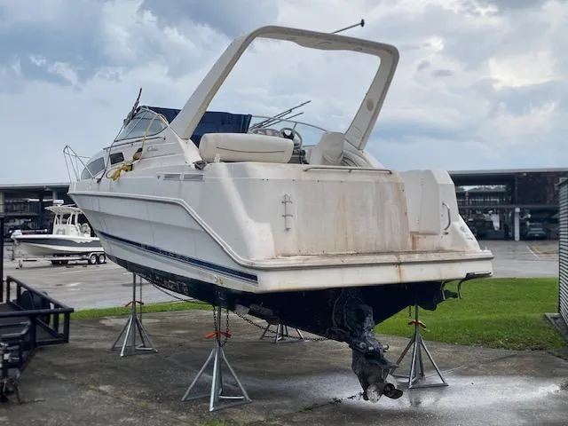 Slide: The Image of 1998 Bayliner Ciara 2855 boat on stands, outdoor storage, cloudy sky background. - 5