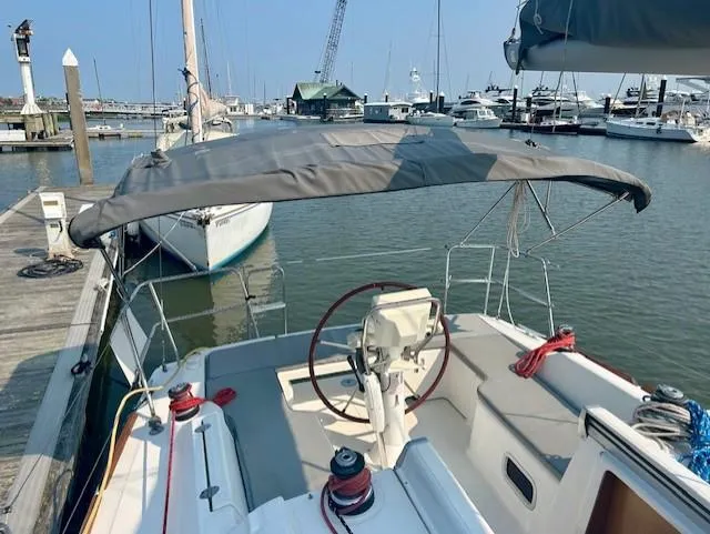 Slide: The Image of 2008 Beneteau Oceanis 31 sailboat docked at marina, featuring a covered cockpit and steering wheel. - 8