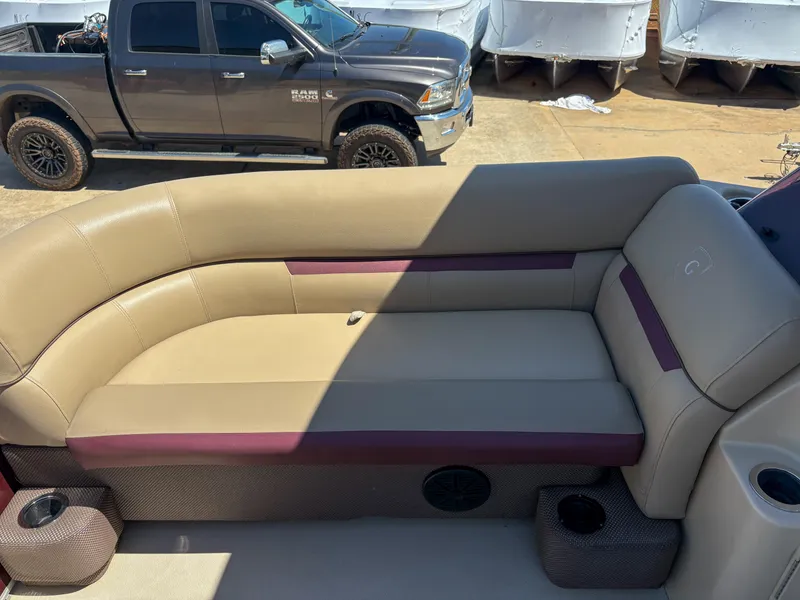 Slide: The Image of 2019 Sweetwater 2186 FS boat interior with beige and maroon seating, parked truck in background. - 5