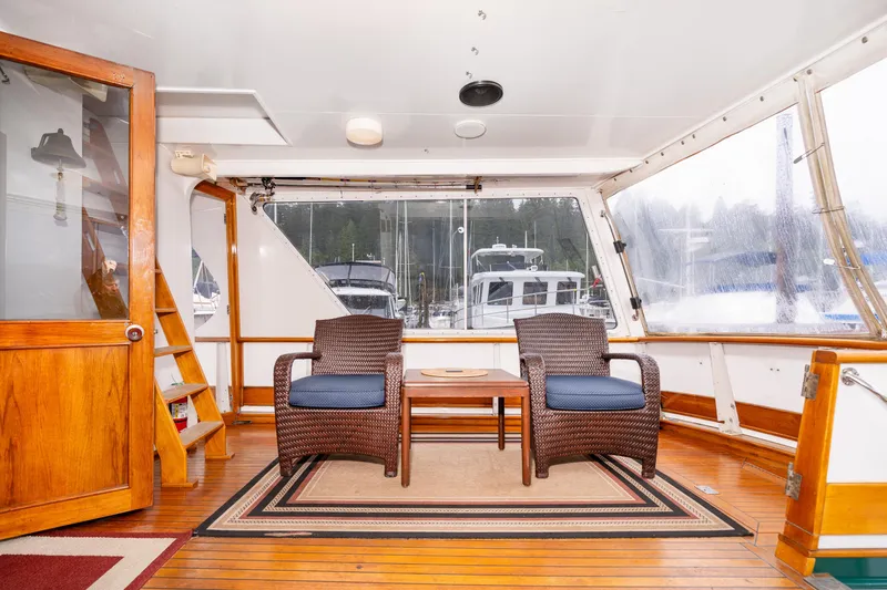 Slide: The Image of Interior of 1980 McQueen Motoryacht with wicker chairs and wooden flooring. - 11